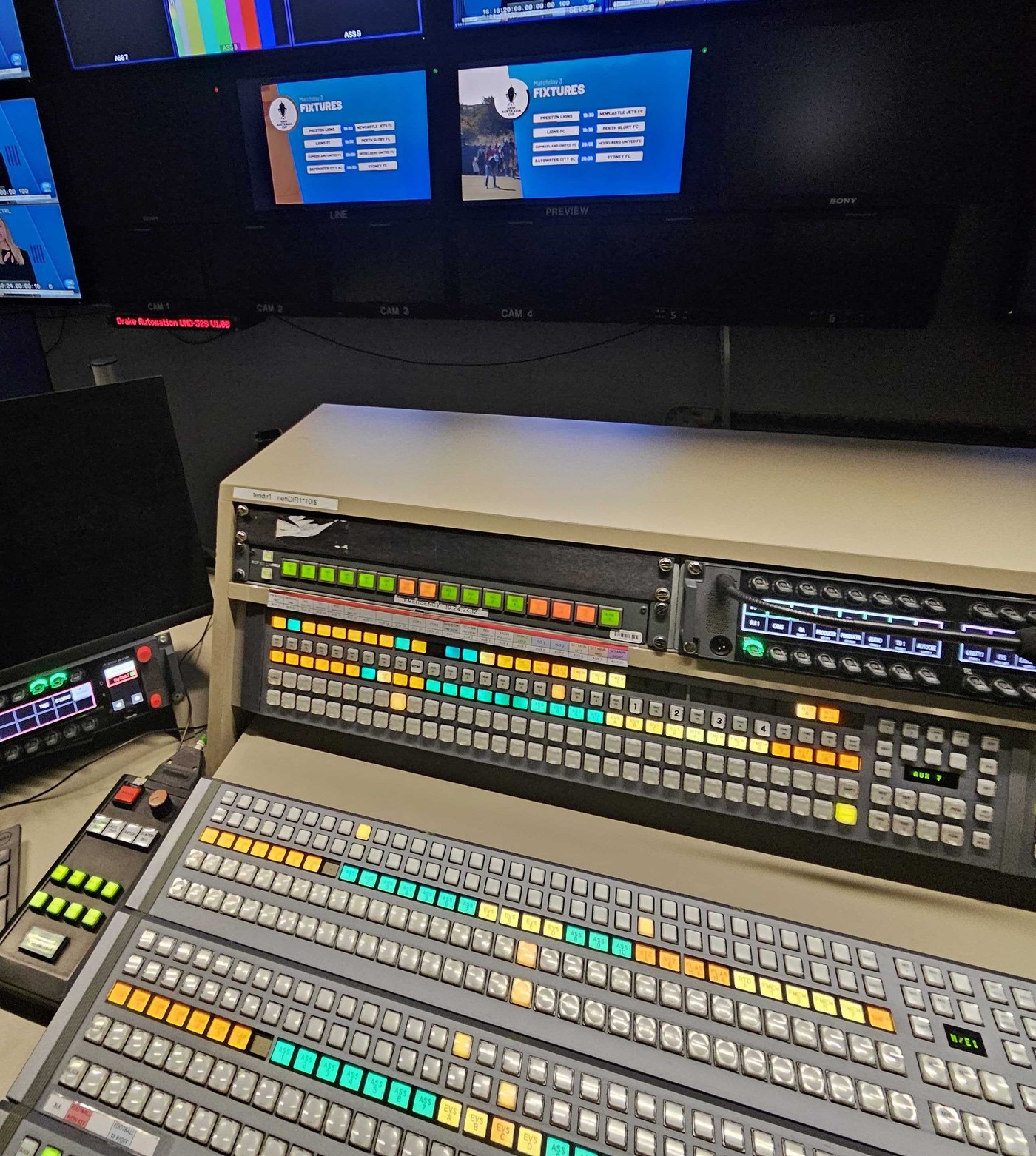 The vision mixer desk in the broadcast gallery with the Australia Cup graphics on the monitor wall